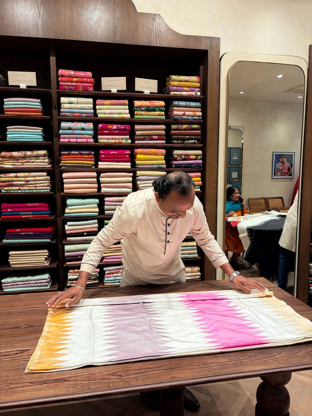 A member of the KALఅA team spreading an ikat saree across the selection table