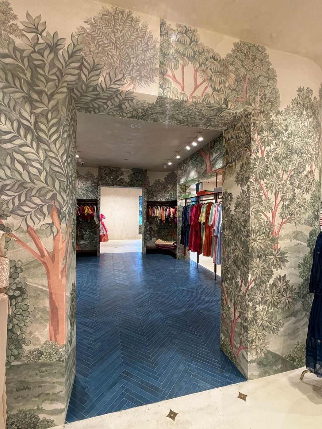 Painted tree mural archway opening onto blue herringbone floors and the blouse section